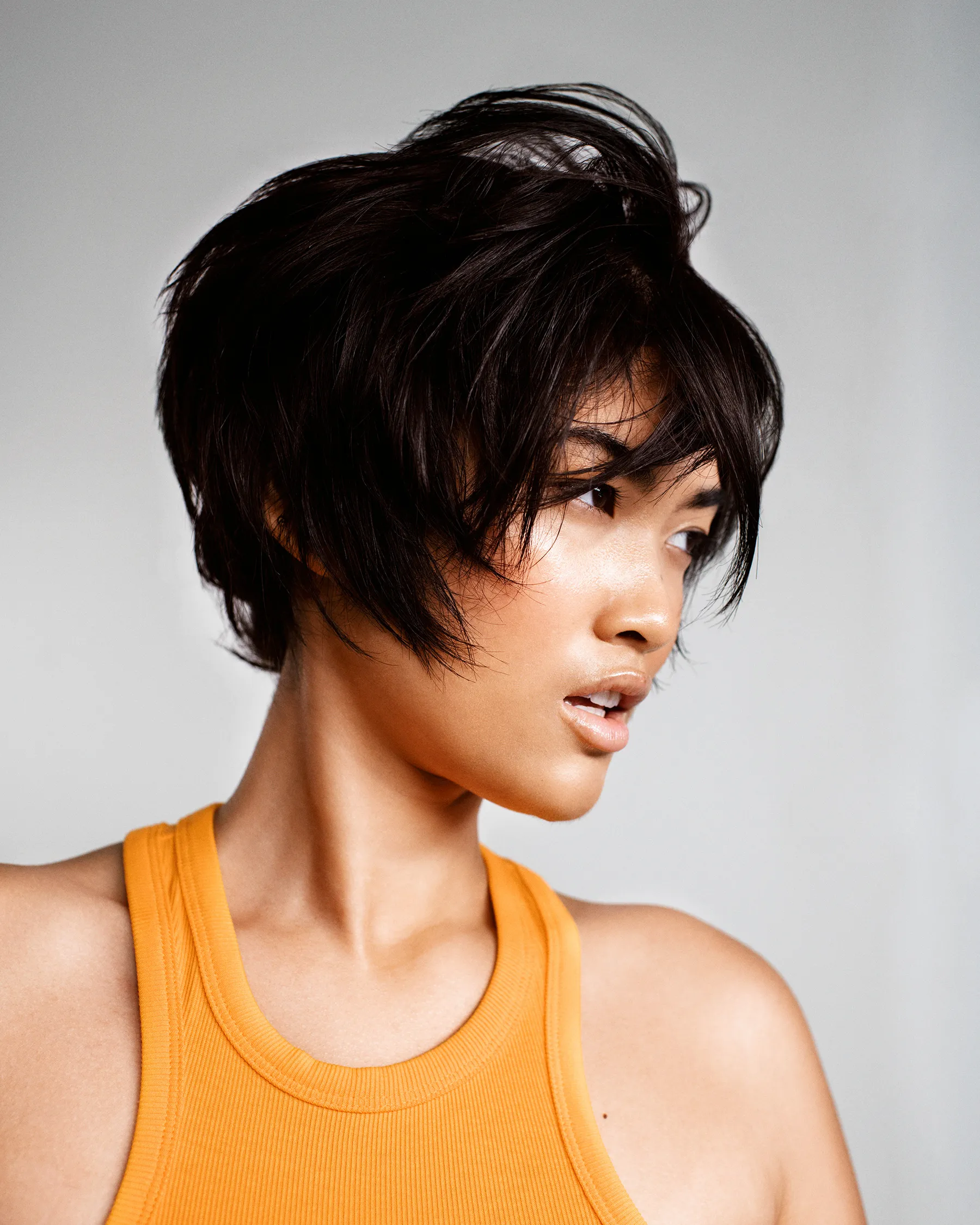 Model with a short textured cut in an orange top, from a Frankie campaign shoot