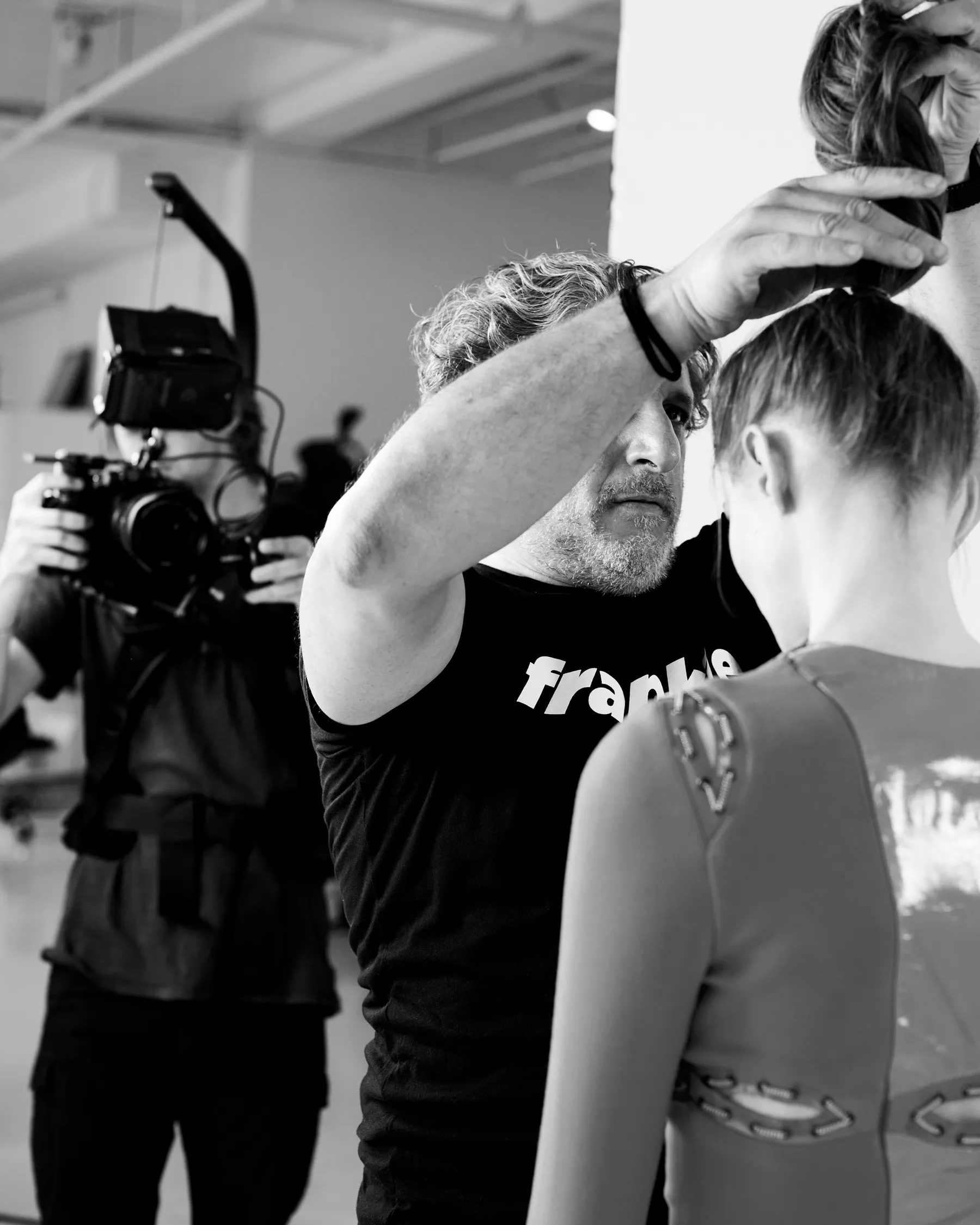 Frank Rizzieri styling hair on a photo set, black and white